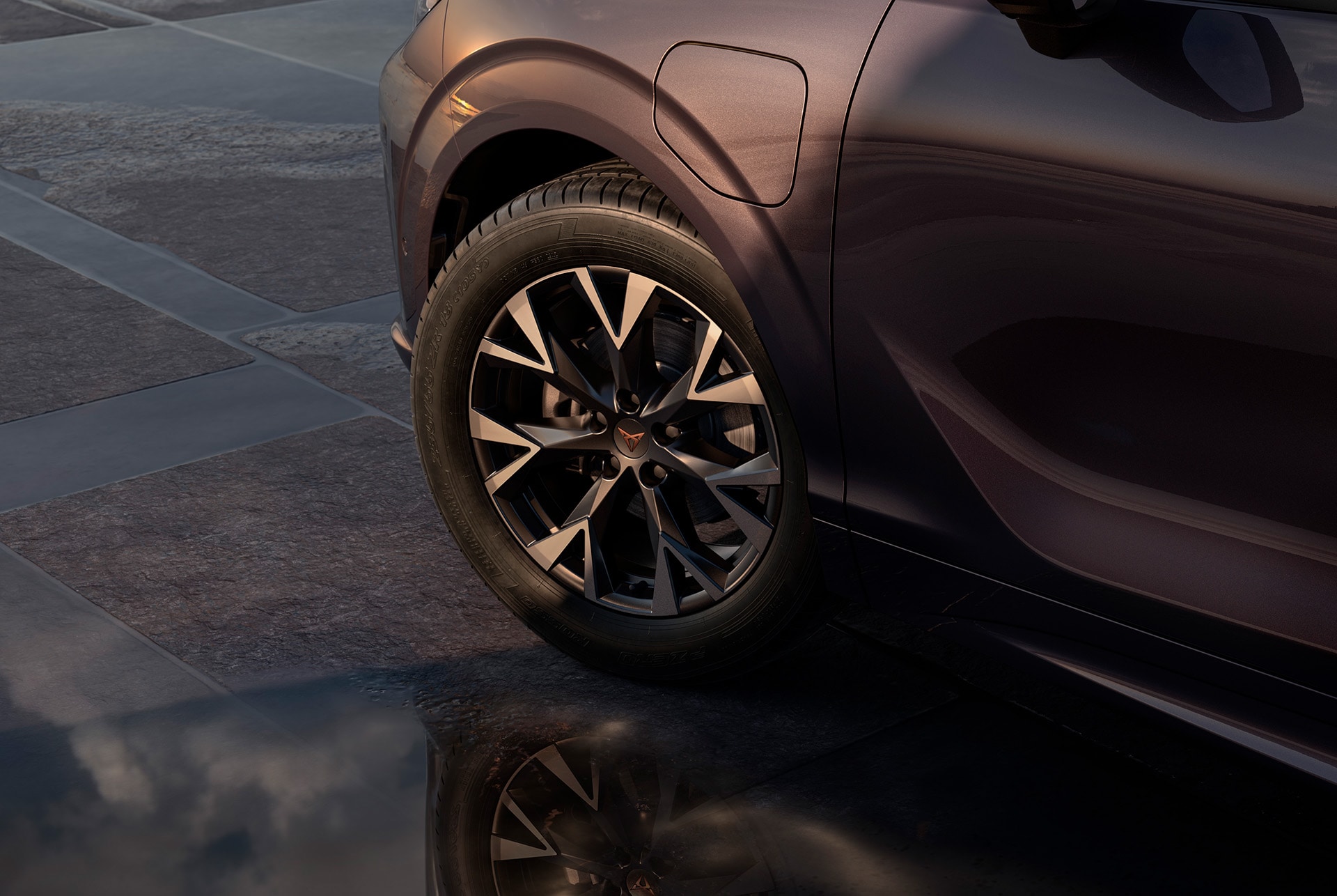 20 inch america's cup wheel on the new cupra terramar, in black with copper accents. Background includes a tiled pavement and part of the car's glossy, dark body.